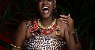 Portrait of an African woman in traditional attire, smiling joyfully.