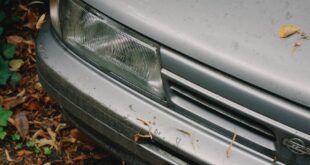 A weathered vintage car surrounded by autumn leaves in Aachen, Germany.