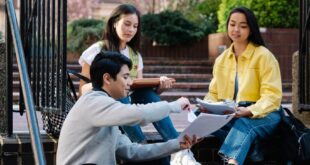 A diverse group of university students studying on outdoor steps, discussing assignments.