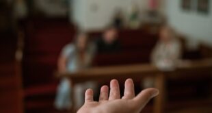A hand reaching out in a church setting, symbolizing faith and community.