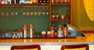 Warm and inviting cocktail bar with illuminated counter and vibrant bottle display in Accra.