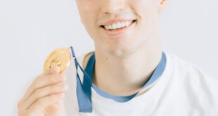 A cheerful young man proudly displaying a gold medal, symbolizing achievement and success.