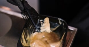 Close-up of stylist mixing hair dye with black brush in salon environment.