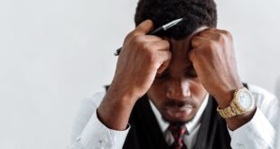 A frustrated businessman sits at a desk reviewing documents, conveying stress and concentration.