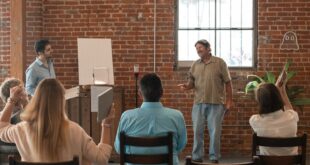 Adults attending a class in a rustic brick-walled room with a wooden ceiling.