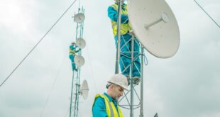 Technicians installing satellite dishes on tower under cloudy sky in Shaqlawa.