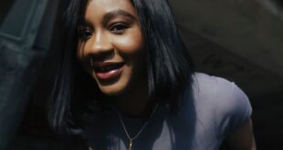 Young woman smiling in cityscape, wearing casual attire under a bridge.