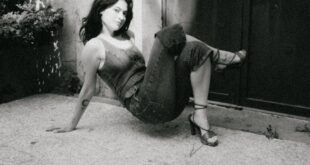 Artistic black and white portrait of a woman posing outdoors on a stone platform.