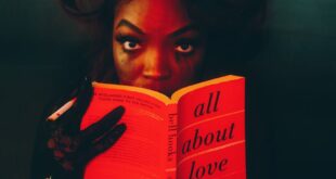 Artistic portrait of woman reading 'All About Love' with dramatic lighting.