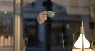 Man in trendy cafe holding a cup, reflecting a relaxed and sophisticated ambiance.