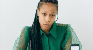 Businesswoman sitting at a desk analyzing charts with a smartphone, highlighting finance and technology.