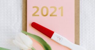 Flat lay of a pregnancy test and tulip on a clipboard with 2021 text.