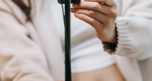 Close-up of a woman setting up a smartphone on a tripod for a vlogging session.