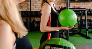 Smiling women enjoying a fitness routine with exercise balls indoors.