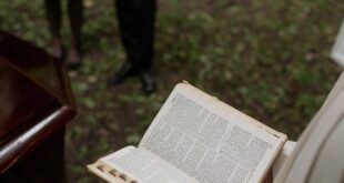 Pastor reading from the Holy Bible during an outdoor funeral service with mourners present.
