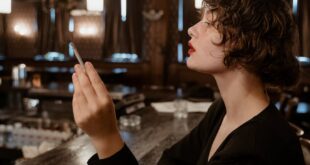 Side view of a fashionable woman smoking in a dimly lit bar, exuding a retro and enigmatic vibe.