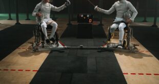 Two wheelchair fencers engaged in a competitive match, showcasing determination and skill.