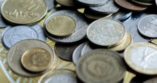 Close-up of various international coins laid on an ornate plate focusing on economy and finance.