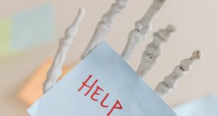 Skeleton hand holding a note with 'HELP' written, symbolizing burnout and stress.
