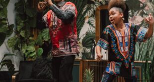 Festive Kwanzaa scene showcasing cultural dance and vibrant traditional clothing indoors.