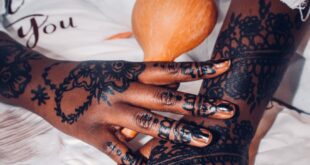 Close-up of hands with detailed henna designs holding a gourd. Artistic and cultural expression.