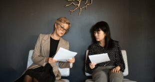 Two women in an office setting reviewing business papers, highlighting teamwork.