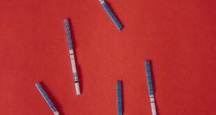 Multiple pregnancy test strips scattered on a vibrant red backdrop, symbolizing fertility and anticipation.