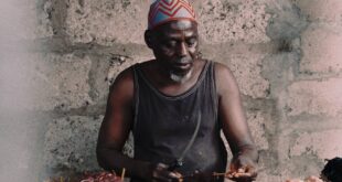 A meat seller prepares cuts at a market stall in Accra, Ghana, showcasing local trade and culture.