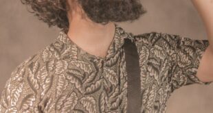 Man in printed shirt with a beard drinks from soda can in a relaxed pose.