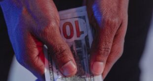 Close-up of handcuffed hands holding US dollars, symbolizing financial crime.