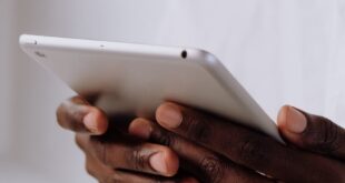 Professional holding a tablet, focusing on hands and technology in a bright setting.