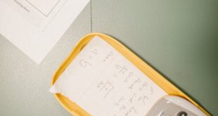 Closeup of a calculator with a hidden cheat sheet during an exam on a green desk.