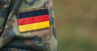 Closeup of German military camouflage uniform with flag patch, symbolizing national pride.