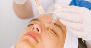 A professional applying serum during a facial treatment in a modern spa setting.