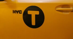 Side view of a vibrant yellow NYC taxi with a clear T logo on the door.