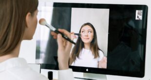 A woman conducts an online makeup tutorial with a digital device indoors, showcasing beauty tips.