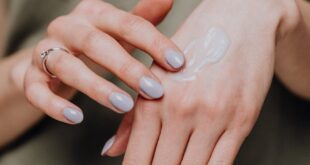 Close-up of female hands applying moisturizer cream for smooth skin care.