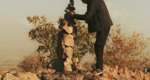 A man building a stone cairn in İncesu, Kayseri, Türkiye during sunset.