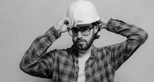 Black and white photo of a male construction worker wearing a hard hat and glasses.