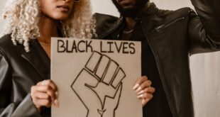Two individuals hold signs advocating Black Lives Matter in a studio setting.