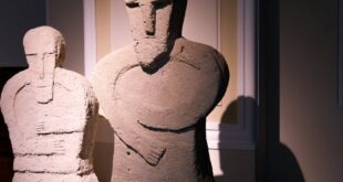 Dramatic lighting highlights ancient stone sculptures in a museum.