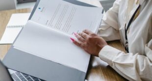 African American woman analyzing financial documents on a laptop, showcasing professional focus.