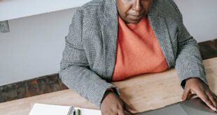 From above of serious African American female working on netbook at table in classroom