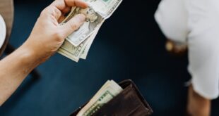 Close-up of hands exchanging cash, representing a financial transaction or payment.