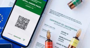 Digital COVID-19 vaccination passport with vials on a desk, symbolizing travel safety.