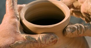 Close-up of hands molding a clay pot, highlighting the art of pottery making.