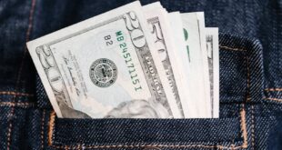 Close-up of US dollar bills in a denim jacket pocket, symbolizing wealth and finance.