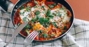 Fresh shakshuka in a skillet with herbs on a table. Perfect for brunch.