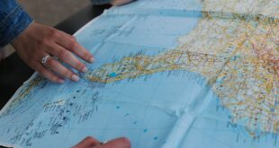 Hands of a young couple planning a road trip using a large map outdoors.