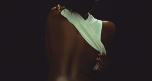 Artistic shot of a woman in jeans with back exposed, vivid and moody lighting.